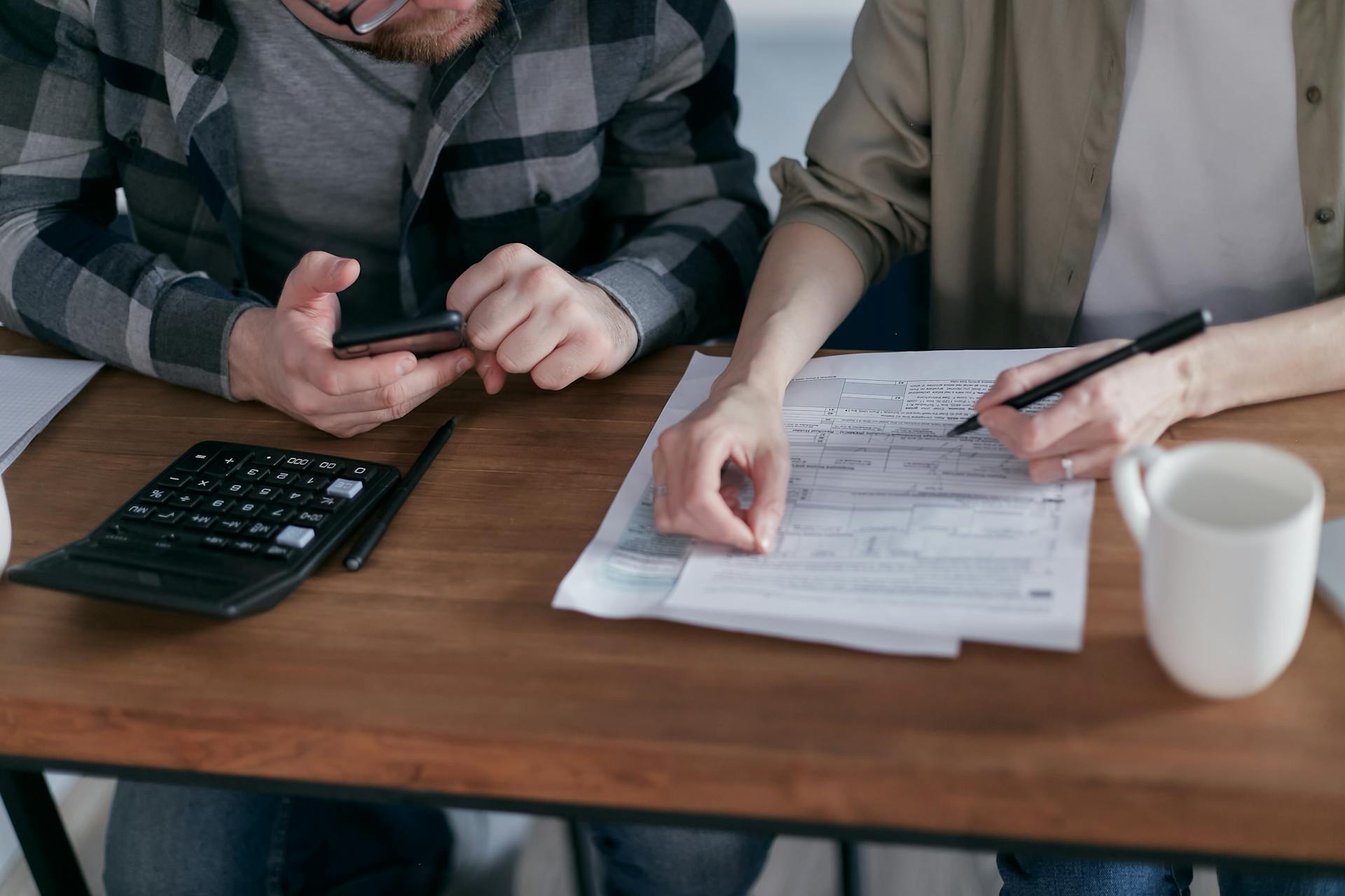 Free A couple diligently reviews their finances using a calculator and documents at home