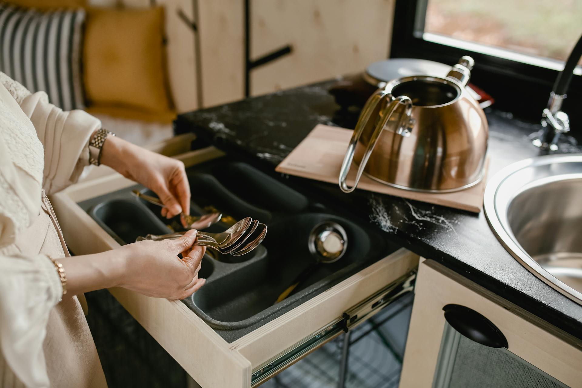 Woman Putting Table Spoons in Drawer