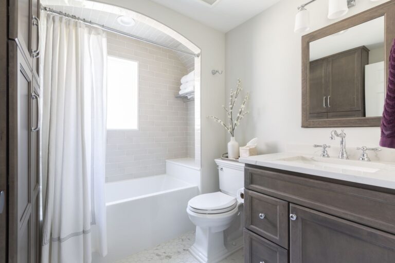 Bathroom Remodeling - Powder Room & Half Bath Statements. Bright hall bathroom with subway-tile tub alcove, wood vanity, and soft neutral finishes.