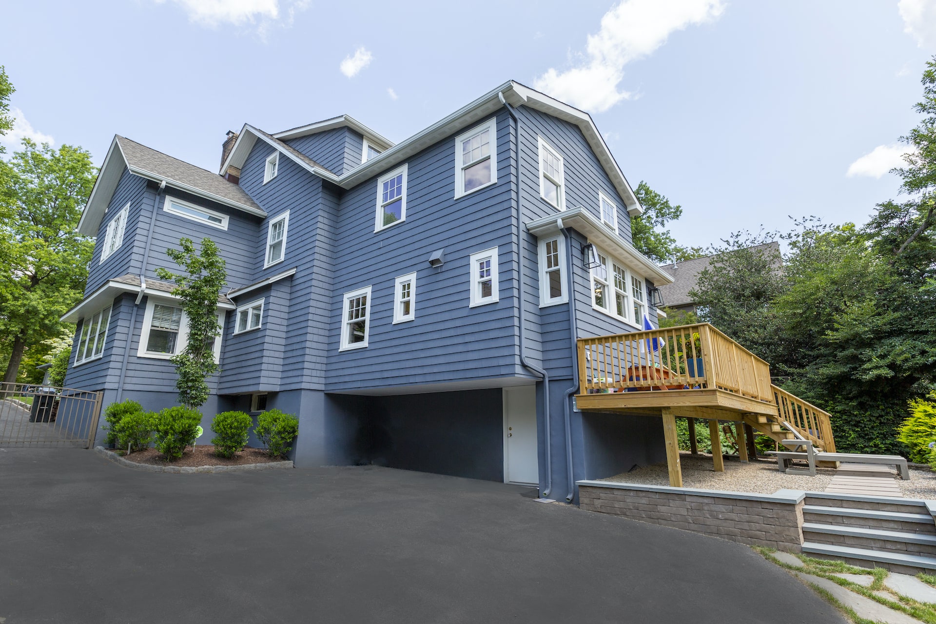 Home additions in NJ featuring elevated wood deck, expanded second floor, and modern siding