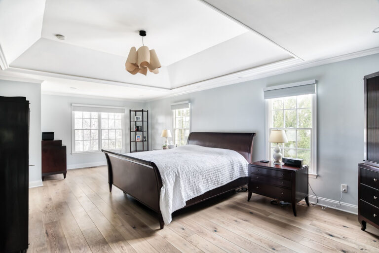 Renovated master bedroom with natural wood floors, tray ceiling, and large windows — part of a Princeton, NJ master suite project by KraftMaster Renovations.