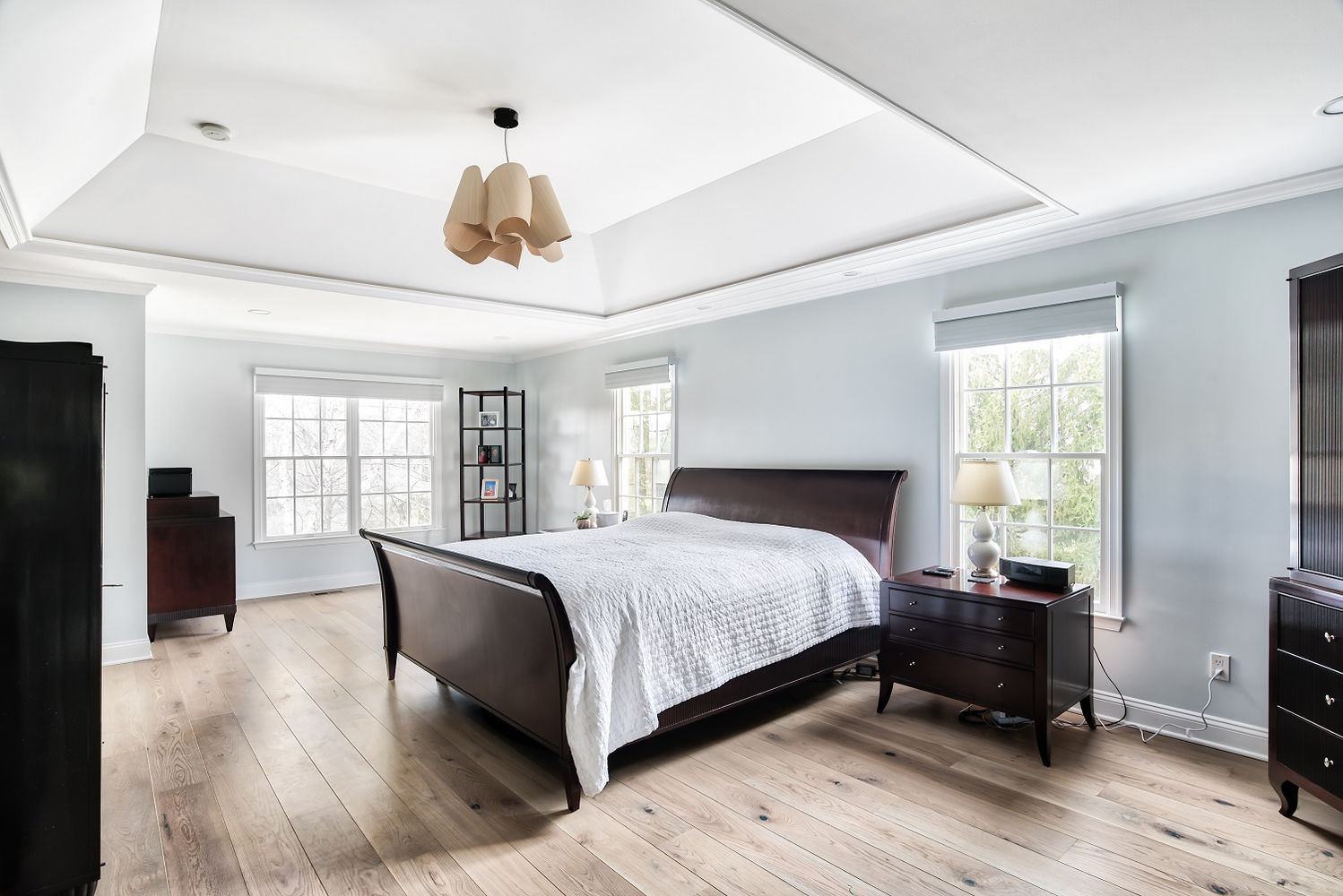Renovated master bedroom with natural wood floors, tray ceiling, and large windows — part of a Princeton, NJ master suite project by KraftMaster Renovations.