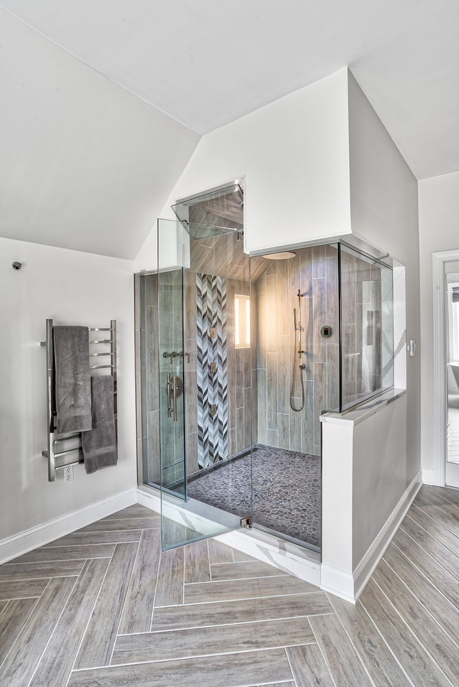 Modern master bathroom with glass-enclosed shower, wood-look tile, and built-in lighting — part of a full suite renovation in Princeton, NJ, by KraftMaster Renovations.