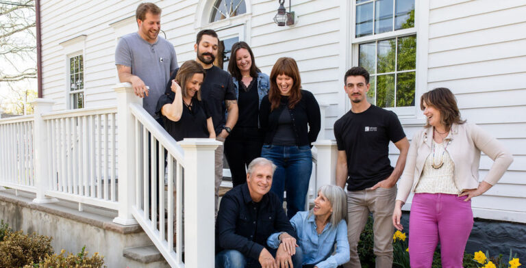 The KraftMaster Renovations team smiling together outside a home, including the owners and family members.