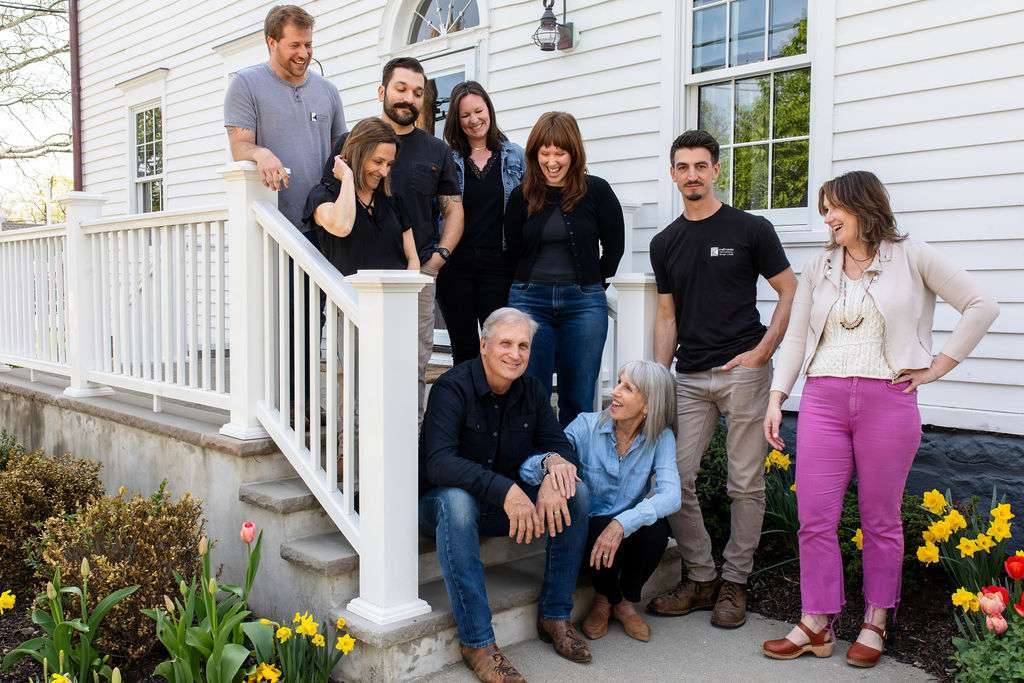 The KraftMaster Renovations team smiling together outside a home, including the owners and family members.