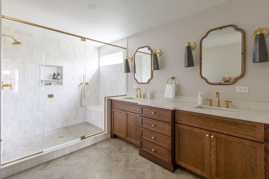 Luxury primary bathroom remodel with double vanity, walk-in shower, and gold fixtures – example of upscale renovation cost range.