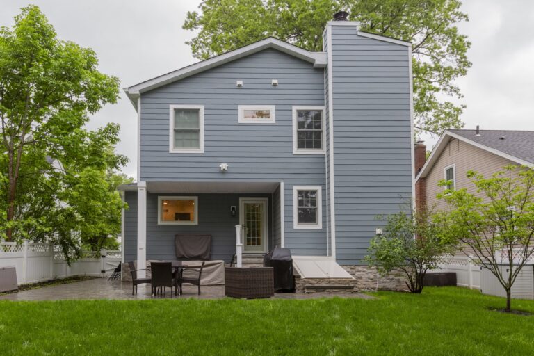 Renovated backyard with modern blue siding, patio, and outdoor seating area.