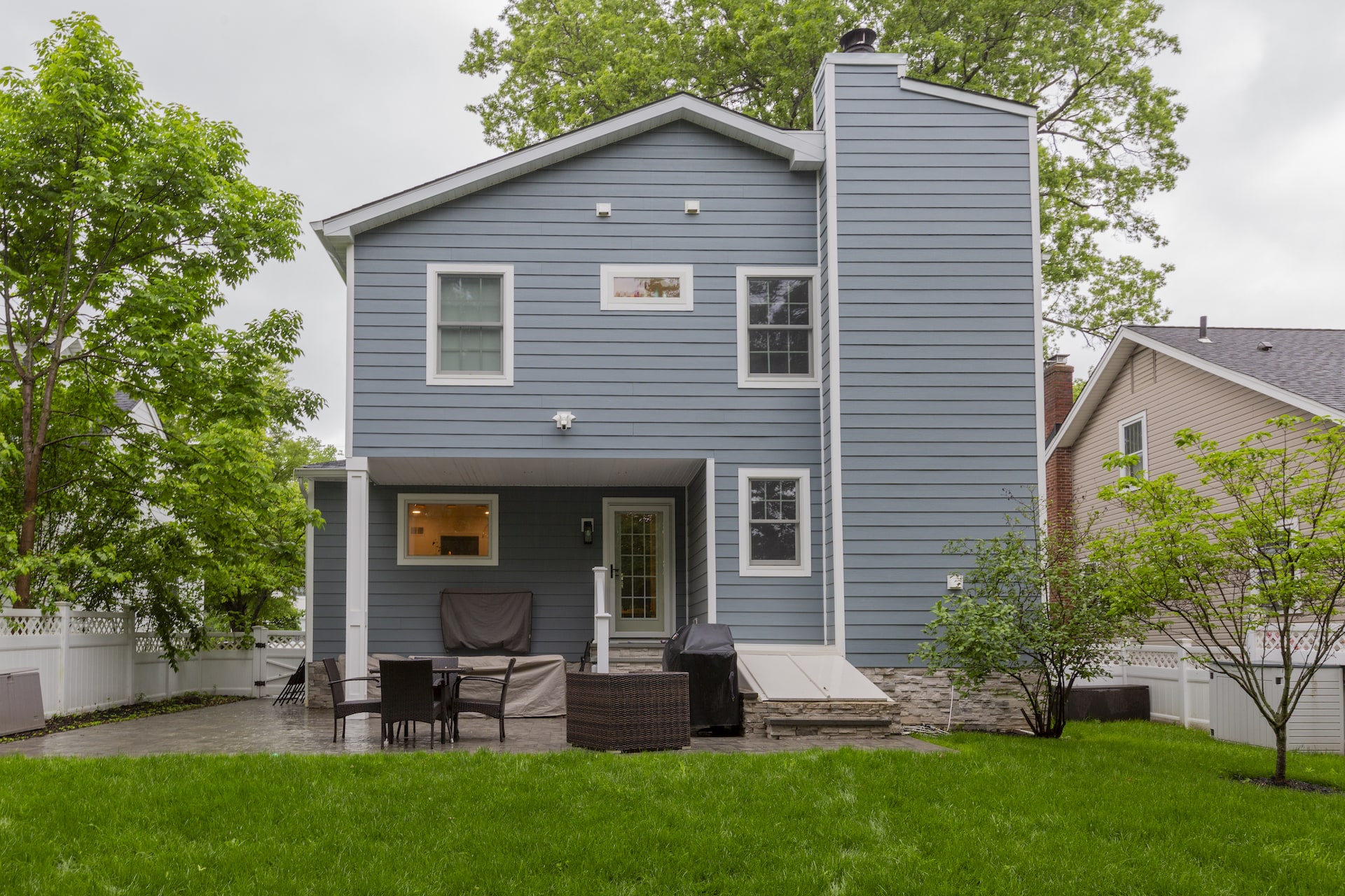 Renovated backyard with modern blue siding, patio, and outdoor seating area.