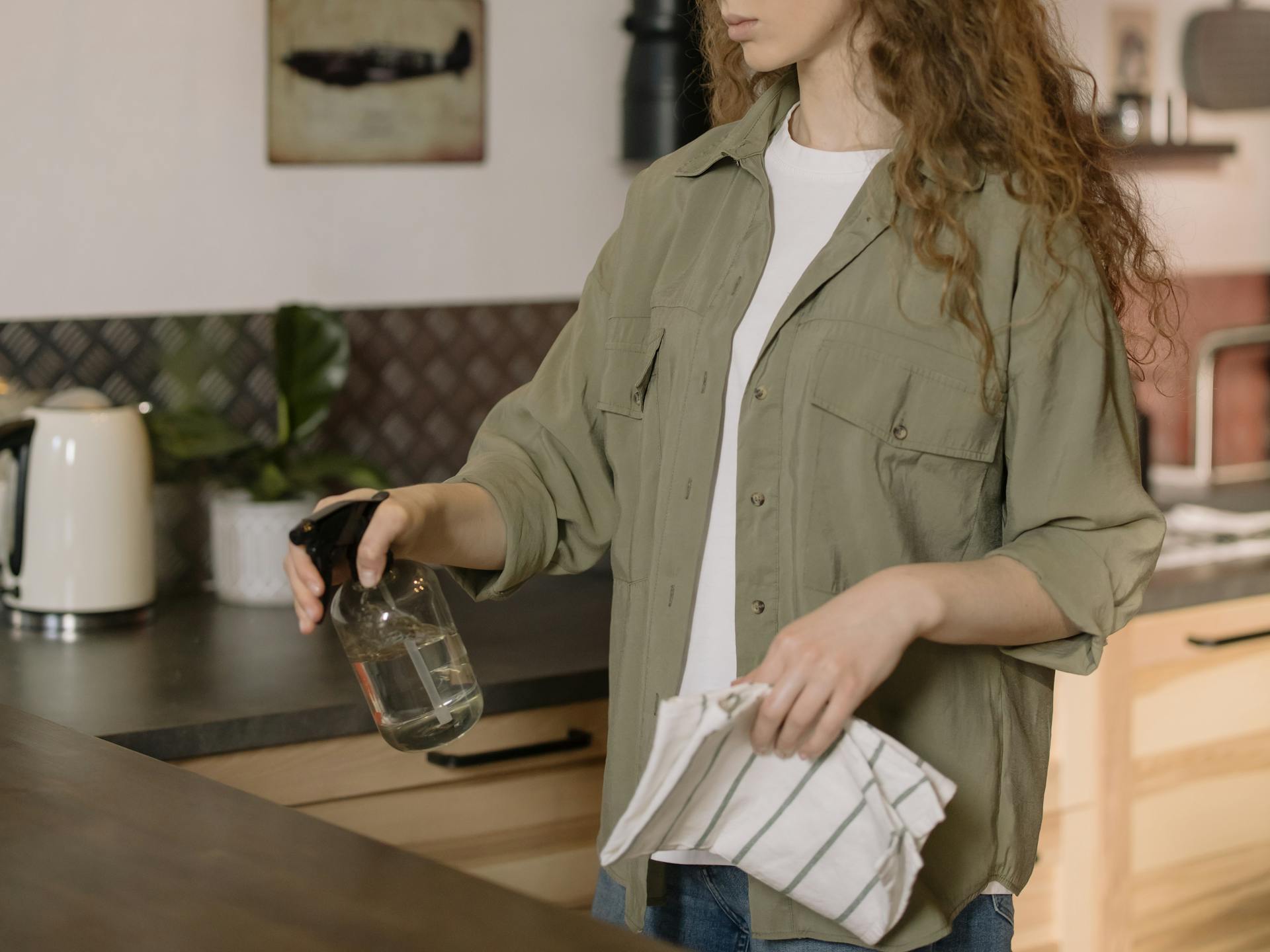 Woman cleaning a kitchen countertop with gentle spray and cloth