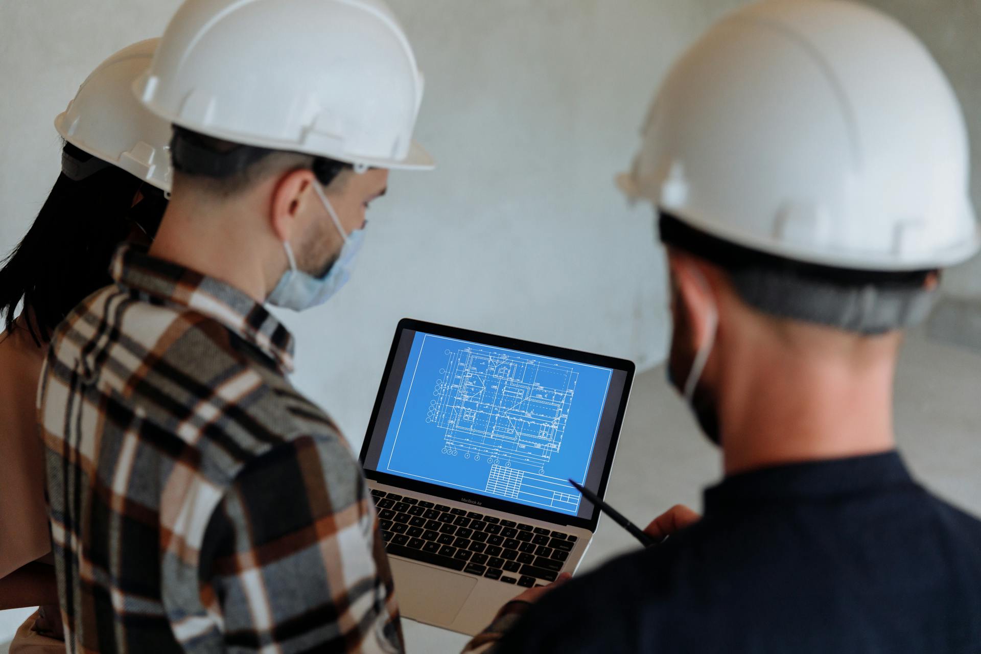 Team of contractors reviewing residential remodel plans on laptop during permit preparation in New Jersey