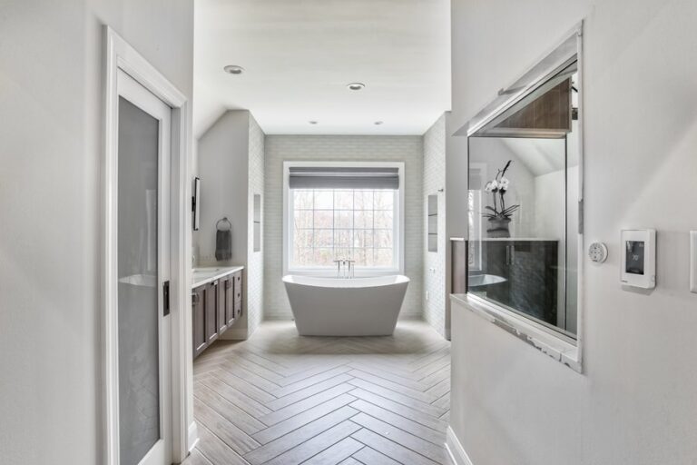 Spa-style master bathroom renovation with freestanding tub, herringbone wood-look tile flooring, and radiant heating — featured by WarmlyYours.