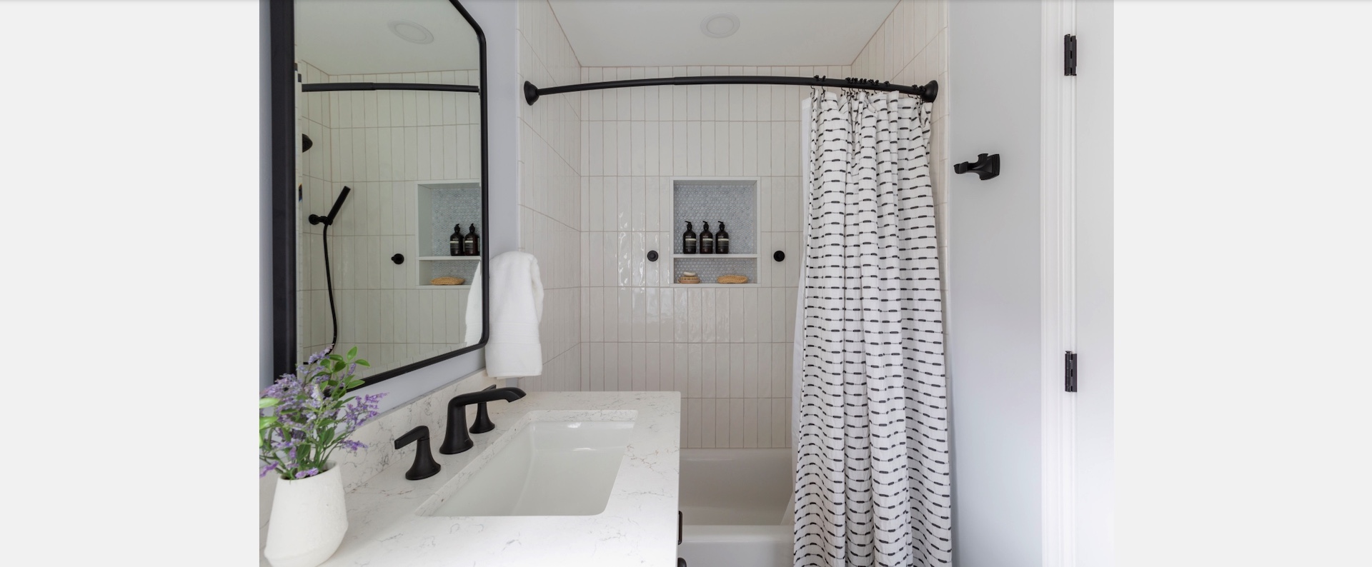 Compact bathroom remodel with white subway tile, black fixtures, niche storage, and shower curtain — designed by KraftMaster Renovations in Chatham, NJ