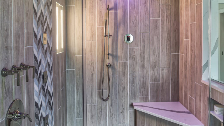 Contemporary steam shower with wood-look tile, integrated lighting, and MrSteam controls — designed by KraftMaster Renovations.