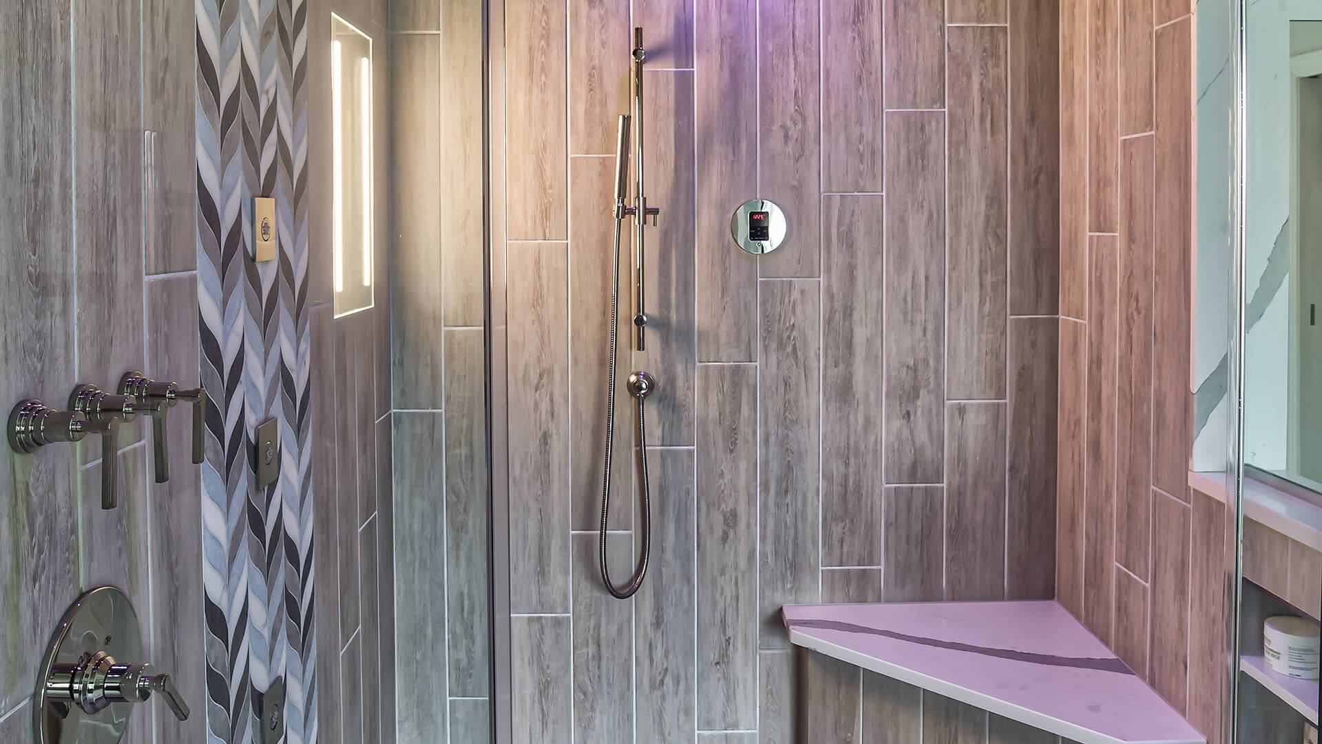 Contemporary steam shower with wood-look tile, integrated lighting, and MrSteam controls — designed by KraftMaster Renovations.