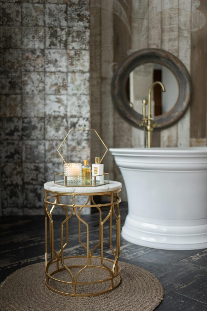 Luxury bathroom detail with freestanding tub, gold accent table, and spa accessories
