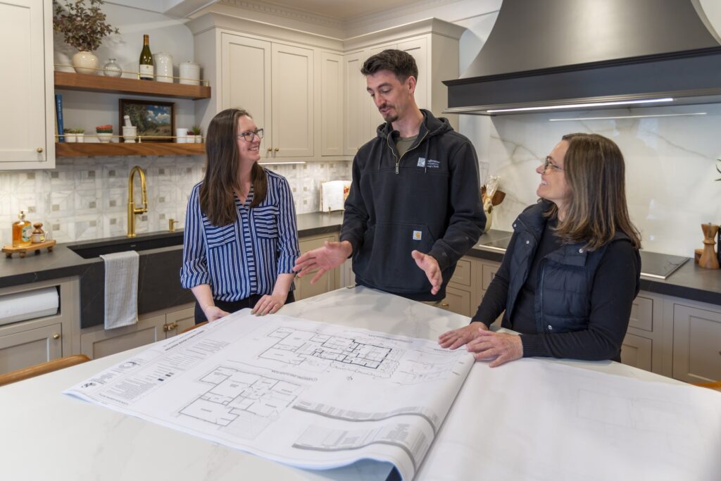 KraftMaster Renovations design team and project manager reviewing architectural plans in kitchen setting