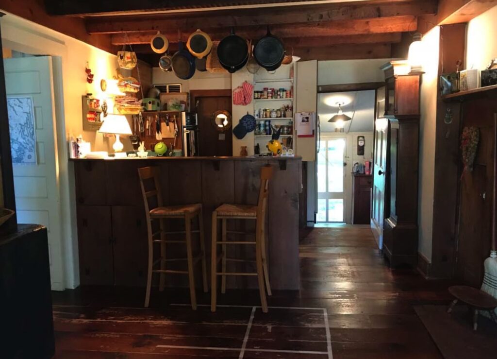 Original kitchen with exposed beams, hanging pots, and rustic wood cabinetry in the historic Price-Baldwin House.