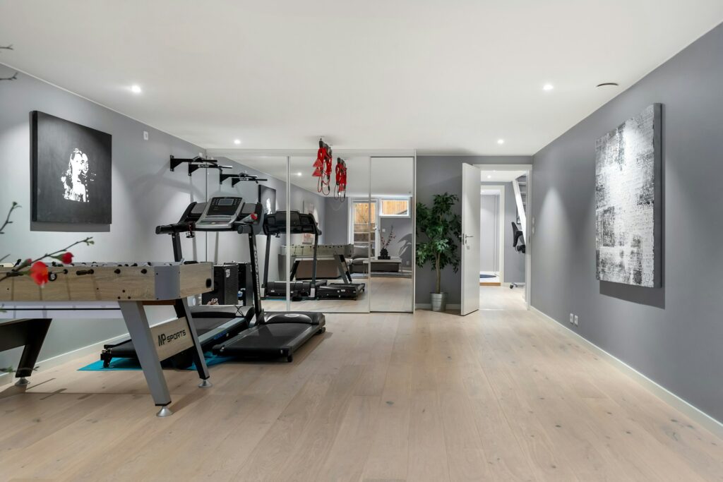 Modern basement remodel featuring a home gym, foosball table, and office area, showcasing flexible multi-use design.