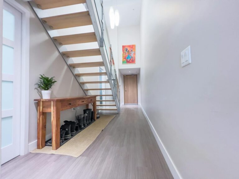 Minimalist hallway with floating staircase and wood console in finished basement