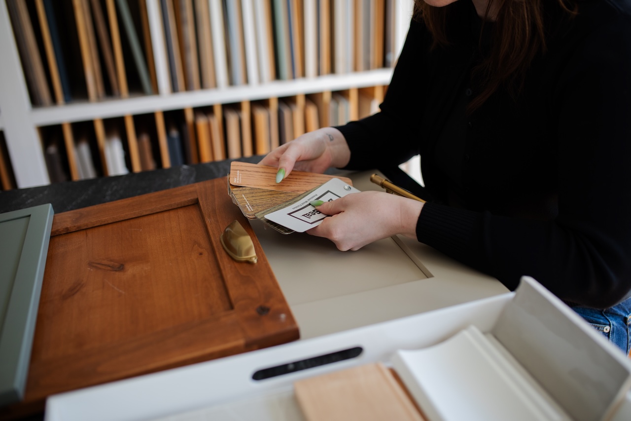 Designer reviewing wood tones and color samples for kitchen cabinetry, highlighting natural finishes and trending palettes