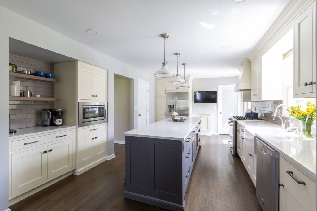 Kitchen featuring soft blue-gray island cabinetry, bright white countertops, and cool-toned finishes, complemented by stainless steel appliances and warm wood floors.
