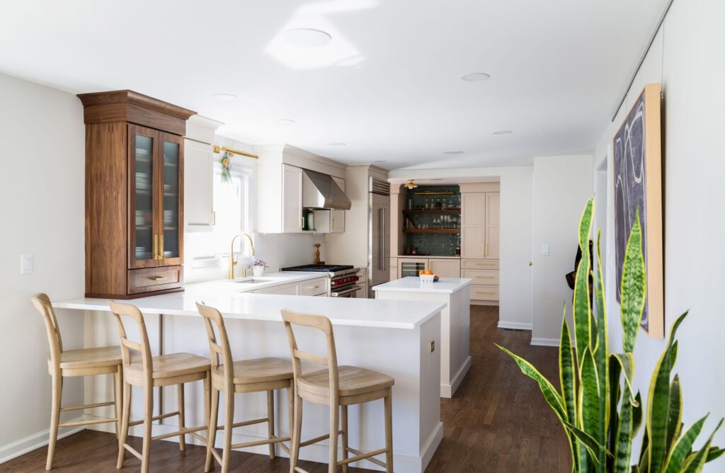 Warm modern kitchen with mushroom-colored cabinetry, natural wood accents, and white quartz countertops in a Chatham home remodel.